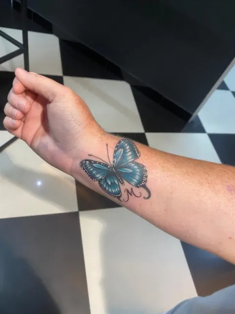 Blue butterfly tattoo on the wrist, by Chad Solomon