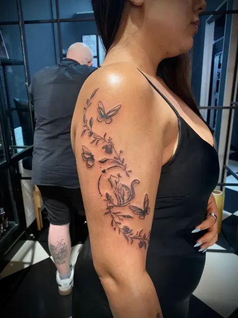 Butterflies and vines tattoo on the upper arm, by Chad Solomon