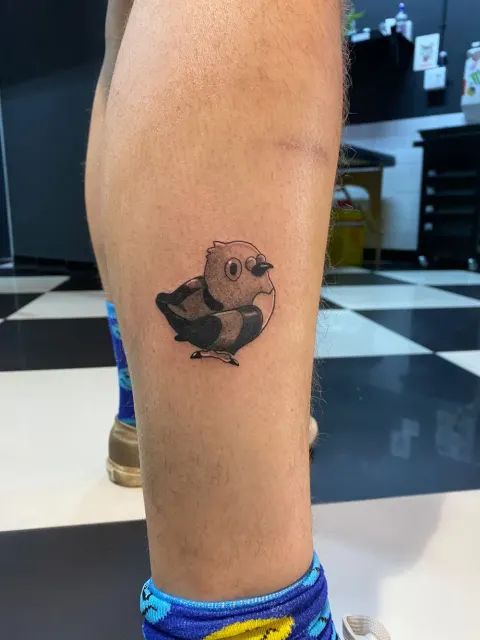 Cartoon bird tattoo on the calf, by Chad Solomon