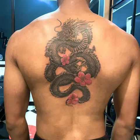 Dragon with pink blossoms tattoo on the full back, by Chad Solomon