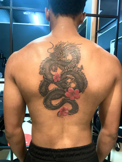 Dragon with pink blossoms tattoo on the full back, by Chad Solomon