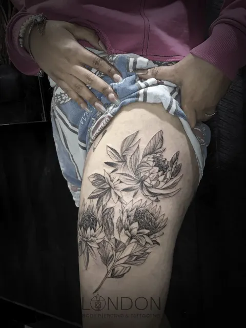 Protea and peony floral piece tattoo on the thigh, by Chad Solomon