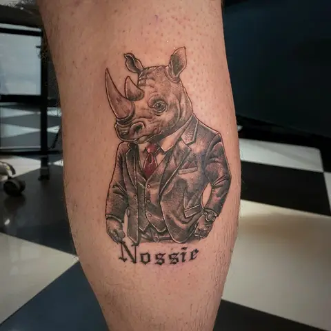 Rhino in a suit and tie tattoo on the calf, by Chad Solomon