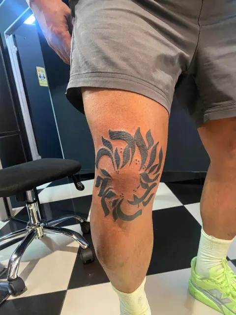 Tribal sun design tattoo on the knee, by Chad Solomon