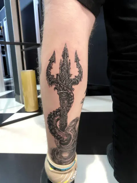 Trident wrapped by octopus tentacles, black and grey calf tattoo, by Chad Solomon