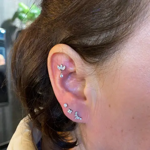 Curated ear with a helix cluster and three lobe piercings, by Chandre Louw