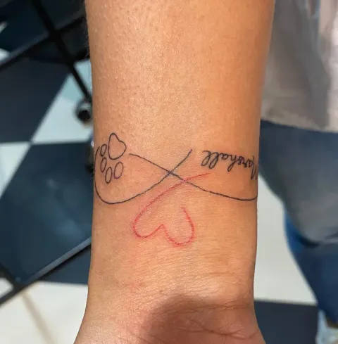 Infinity sign with paw prints and a heart tattoo on the wrist, by Kayla Grimwood