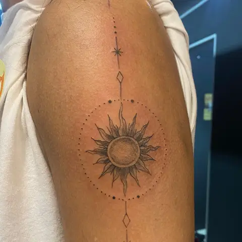 Ornamental sun with dotwork tattoo on the upper arm, by Kayla Grimwood