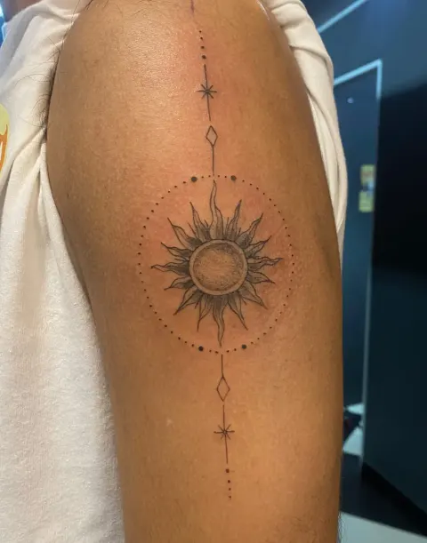 Ornamental sun with dotwork tattoo on the upper arm, by Kayla Grimwood