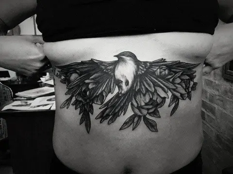 Bird with spread wings and peonies across the sternum and ribs, by Rob Turner