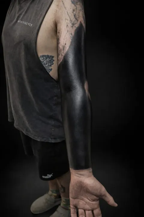 Solid blackout sleeve tattoo on the full arm, by Rob Turner