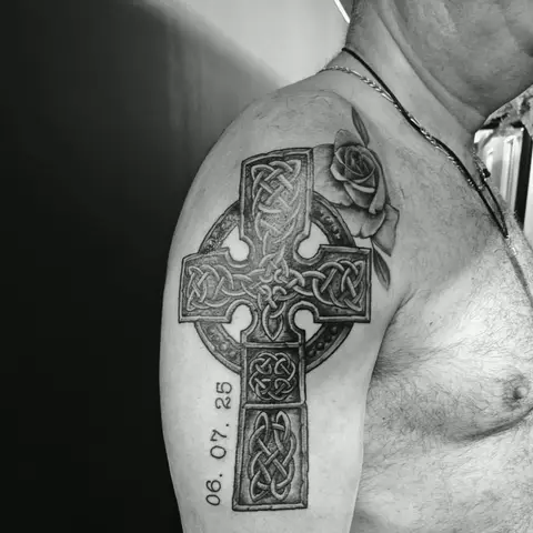Celtic cross with a rose and memorial date tattoo on the upper arm, by Rob Turner