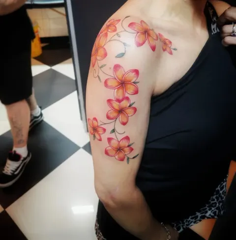 Pink and orange frangipani flowers tattoo on the shoulder and upper arm, by Rob Turner