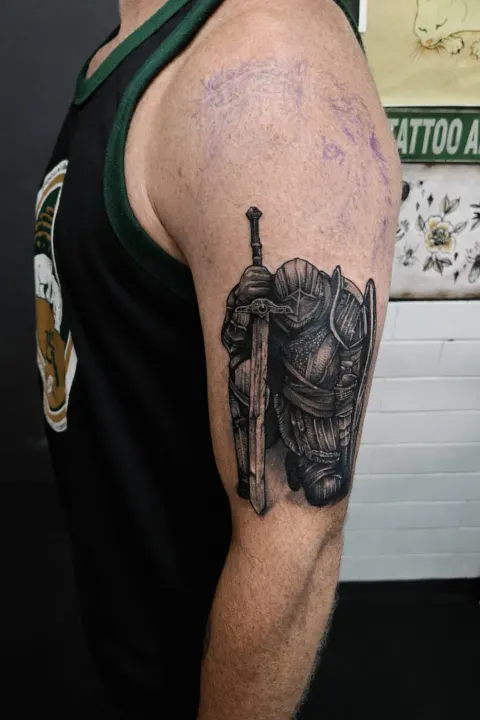 Armoured knight with a sword tattoo on the upper arm, by Rob Turner