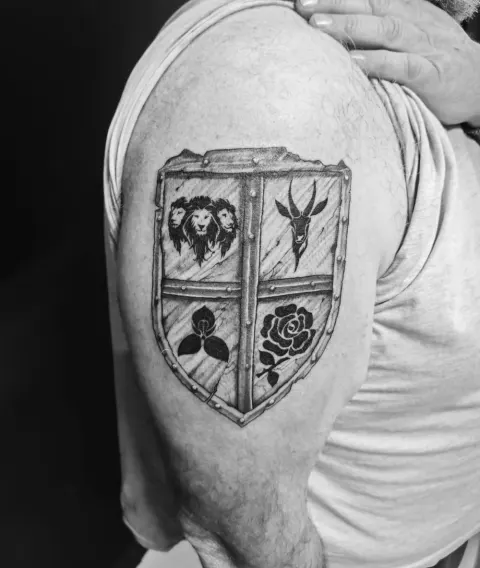 Shield crest with a lion, antelope, clover and rose on the upper arm, by Rob Turner
