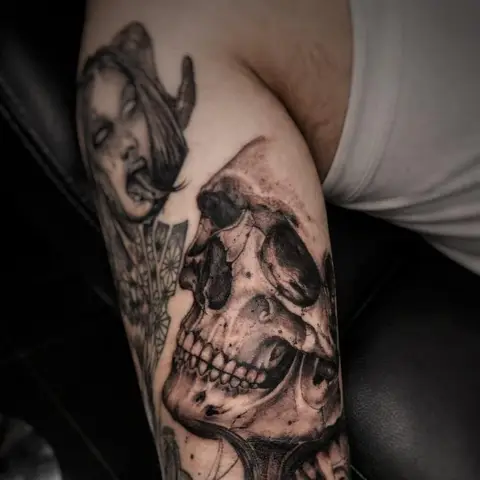 Dark skull sleeve tattoo on the arm, by Rob Turner