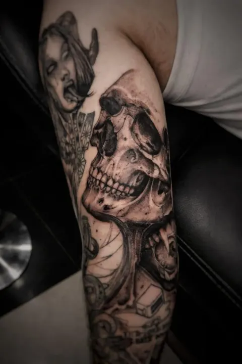 Dark skull sleeve tattoo on the arm, by Rob Turner
