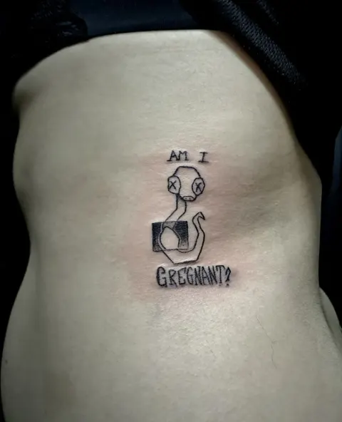 Am I pregnant meme tattoo with a cartoon figure, by Tayla Symons