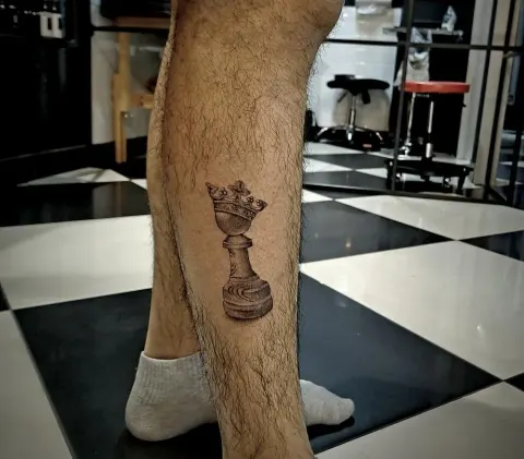 Chess king piece tattoo on the calf, by Tayla Symons