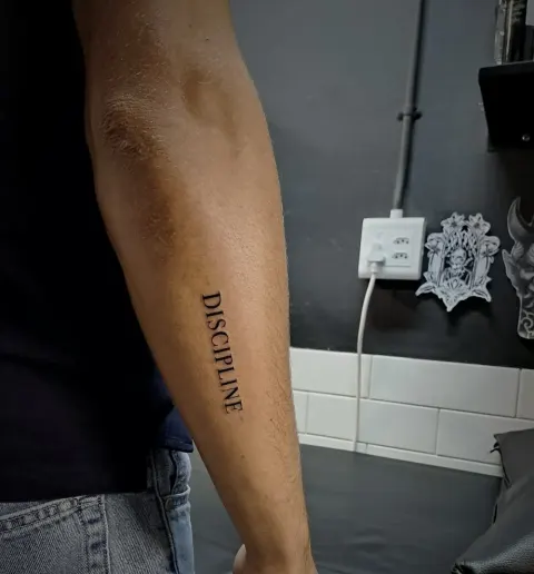 Discipline lettering down the forearm, by Tayla Symons