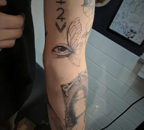 Eye with a butterfly wing, dotwork arm tattoo, by Tayla Symons