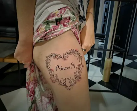 Floral heart wreath with script tattoo on the thigh, by Tayla Symons