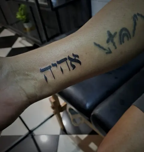 Hebrew script tattoo on the forearm, by Tayla Symons