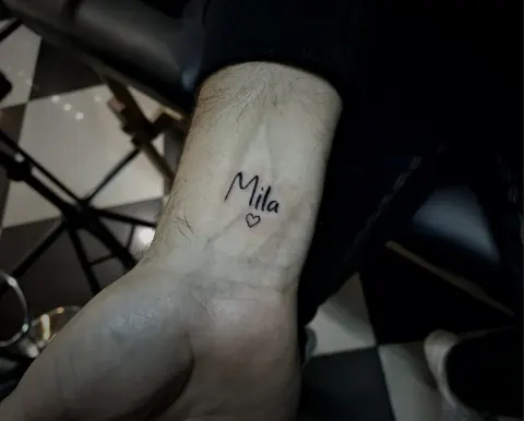 Name with a small heart tattoo on the wrist, by Tayla Symons