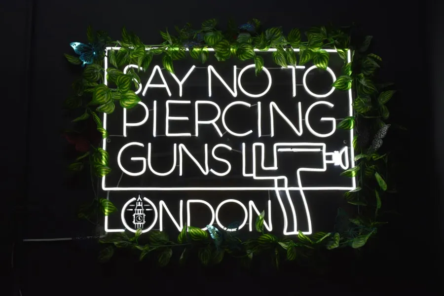 Neon sign in the London Body & Ink studio reading Say no to piercing guns